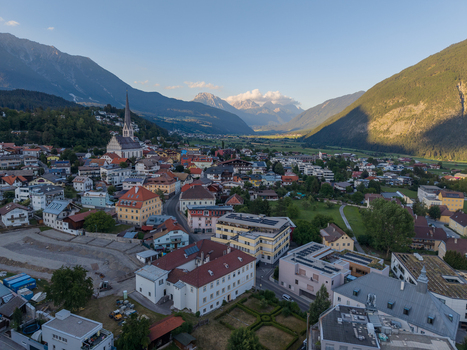 Aerial view of the town of Imst in the Austrian Alps featuring historic architecture a prominent church spire and surrounding mountain valleys. Imst Tyrol Austria.