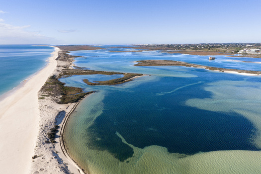 Aerial view of Praia da Fuseta showing the sandy coastline turquoise lagoon waters and tidal channels in Fuseta Faro District Portugal. Aerial view of Praia da Fuseta showing the sandy coastline turquoise lagoon waters and tidal channels in Fuseta Faro District Portugal.