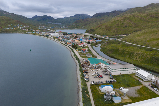 Aerial view of the coastal town of Unalaska featuring colorful houses industrial buildings satellite dishes and a harbor nestled between green mountains in Unalaska Alaska United States.
