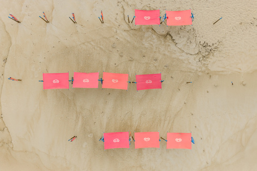 Aerial view of pink sunshades arranged in rows on the sandy beach of Praia de Sao Pedro de Moel Marinha Grande Leiria Portugal. Aerial view of pink sunshades arranged in rows on the sandy beach of Praia de Sao Pedro de Moel Marinha Grande Leiria Portugal.