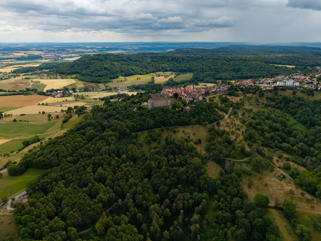 Aerial view of Schloss Waldenburg situated on a hill surrounded by dense forests and the town rooftops under a cloudy sky in Waldenburg Sachsen Germany. Aerial view of Schloss Waldenburg situated on a hill surrounded by dense forests and the town rooftops under a cloudy sky in Waldenburg Sachsen Germany.