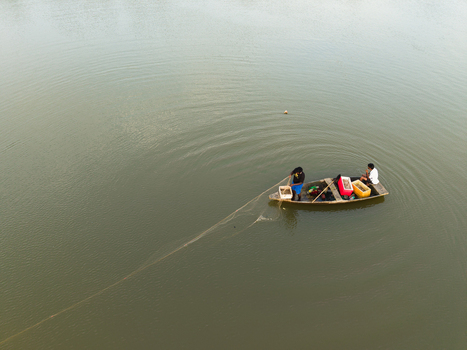 Aerial view of fishermen in a small wooden boat pulling a fishing net on calm water in Galle Southern Province Sri Lanka. Aerial view of fishermen in a small wooden boat pulling a fishing net on calm water in Galle Southern Province Sri Lanka.