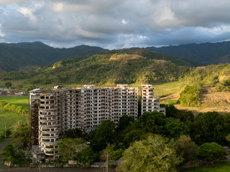 Aerial view of the abandoned Sonesta One Resort building surrounded by dense tropical forest and rolling green hills under a dramatic sky Jaco Provincia de Puntarenas Costa Rica. Aerial view of the abandoned Sonesta One Resort building surrounded by dense tropical forest and rolling green hills under a dramatic sky Jaco Provincia de Puntarenas Costa Rica.