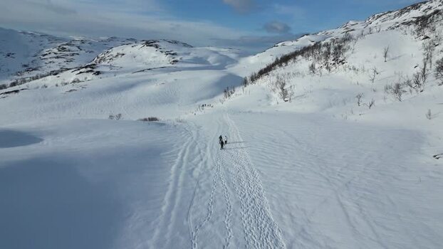 Aerial view of people walking on a snowy trail in Kvaloya Norway.