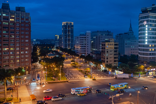 View of Xiaonanmen gate surrounded by illuminated city buildings and busy traffic at an intersection in Zhongzheng District Taipei City Taiwan.