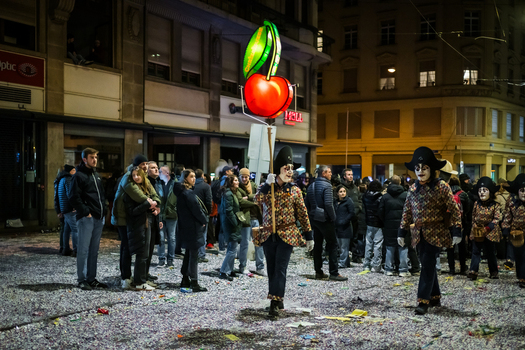 Basel Switzerland 10 March 2025 View of a vibrant Fasnacht street scene alive with masked figures in patterned coats amidst a confetti strewn ground. Basel Switzerland 10 March 2025 View of a vibrant Fasnacht street scene alive with masked figures in patterned coats amidst a confetti strewn ground.