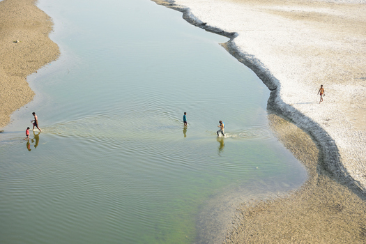 Kushtia District Khulna Division Bangladesh 10 March 2020 View of people wading through the shallow waters of a calm river with sandy banks under clear daylight. Kushtia District Khulna Division Bangladesh 10 March 2020 View of people wading through the shallow waters of a calm river with sandy banks under clear daylight.