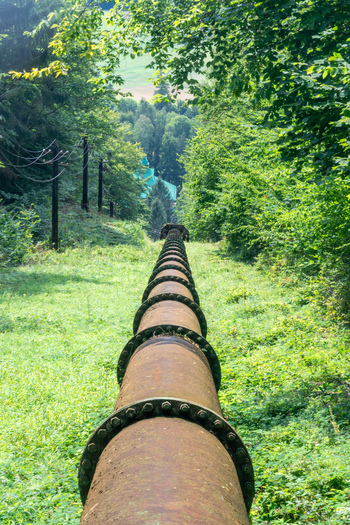 View of the historic pipeline of the Jasenie Hydroelectric Power Plant extending through a lush green forest in Jasenie Banska Bystrica Regio Slovakia.