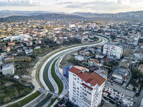 Aerial view of the Gjanica River flowing through the urban landscape of Fier with residential buildings and a bridge in Fier Fier County Albania.