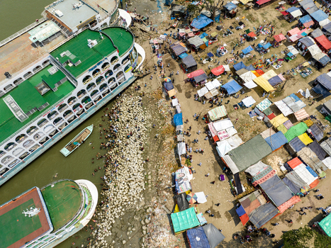 Aerial view of colorful makeshift stalls sprawling along the riverbank next to docked ferries a vibrant scene of commerce and transport Charmonai Barisal Division Bangladesh. Aerial view of colorful makeshift stalls sprawling along the riverbank next to docked ferries a vibrant scene of commerce and transport Charmonai Barisal Division Bangladesh.