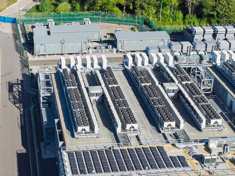 Aerial view of a data center facility with rows of industrial cooling units and solar panels on the roof United Kingdom.