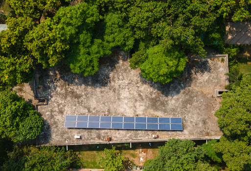 Lahore Pakistan 08 September 2026 Aerial view of solar panels installed on the flat roof of a government office building surrounded by lush green trees.