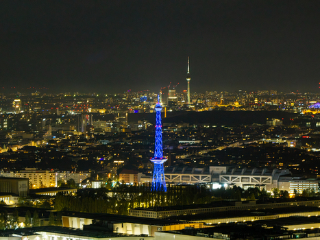 Aerial view of the illuminated Funkturm Berlin tower at night surrounded by the sprawling cityscape and glowing street lights of Berlin Berlin Germany.