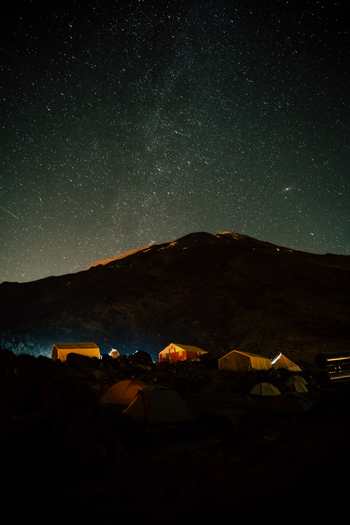 View of Mount Ararat at night with a base camp of tents illuminated under a starry sky in Turkey.