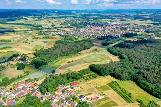 Aerial view of the historic town center surrounded by lush green fields dense forests and rolling hills under a bright blue sky in Neunkirchen am Brand Bavaria Germany. Aerial view of the historic town center surrounded by lush green fields dense forests and rolling hills under a bright blue sky in Neunkirchen am Brand Bavaria Germany.