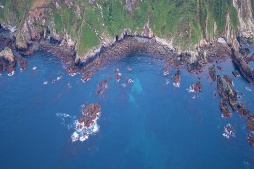 Aerial view of steep green cliffs and dark rocky shores meeting the deep blue waters of the Cantabrian Sea Cudillero Asturias Spain. Aerial view of steep green cliffs and dark rocky shores meeting the deep blue waters of the Cantabrian Sea Cudillero Asturias Spain.