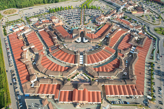 Aerial view of Designer Outlet Serravalle with its distinctive circular architecture red tiled roofs and expansive parking areas Serravalle Scrivia Piemonte Italy. Aerial view of Designer Outlet Serravalle with its distinctive circular architecture red tiled roofs and expansive parking areas Serravalle Scrivia Piemonte Italy.