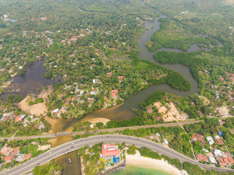 Aerial view of Devil s Rock and the winding river surrounded by lush tropical greenery and coastal settlements in Ahangama Southern Province Sri Lanka. Aerial view of Devil s Rock and the winding river surrounded by lush tropical greenery and coastal settlements in Ahangama Southern Province Sri Lanka.