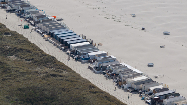 Aerial view of a long row of beach houses and small holiday huts situated between sandy dunes and the wide beach Velsen Noord Noord Holland Netherlands.