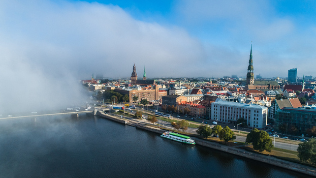 Aerial view of the historic skyline of Riga with St. Peters Church and Riga Cathedral emerging from morning fog along the Daugava River Riga Latvia. Aerial view of the historic skyline of Riga with St. Peters Church and Riga Cathedral emerging from morning fog along the Daugava River Riga Latvia.