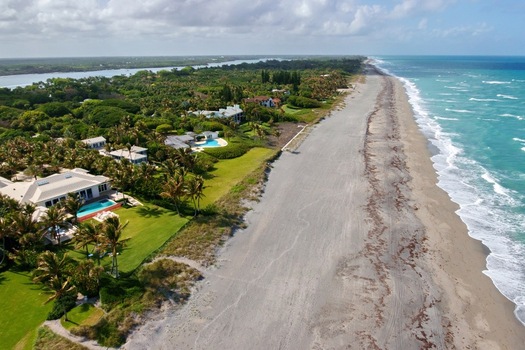 Aerial view of golden sands meet the turquoise ocean fringed by lush green estates and the tranquil Intracoastal Waterway Jupiter Island Florida United States. Aerial view of golden sands meet the turquoise ocean fringed by lush green estates and the tranquil Intracoastal Waterway Jupiter Island Florida United States.