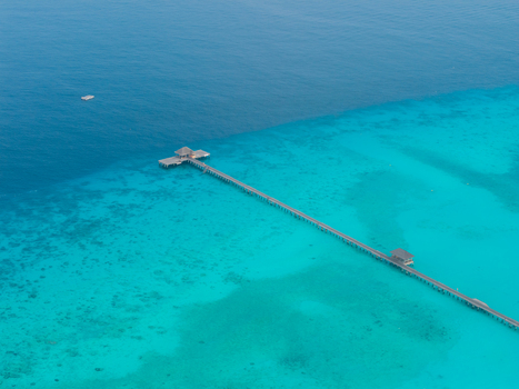 Aerial view of a long pier stretching over turquoise shallows to meet the sapphire sea Hoarafushi Thiladhunmathee Uthuruburi Maldives. Aerial view of a long pier stretching over turquoise shallows to meet the sapphire sea Hoarafushi Thiladhunmathee Uthuruburi Maldives.