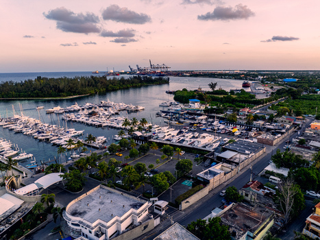 Aerial view of Club Nautico de Santo Domingo Inc. featuring numerous yachts docked in the marina surrounded by lush greenery and coastal infrastructure in Andres Santo Domingo Dominican Republic. Aerial view of Club Nautico de Santo Domingo Inc. featuring numerous yachts docked in the marina surrounded by lush greenery and coastal infrastructure in Andres Santo Domingo Dominican Republic.