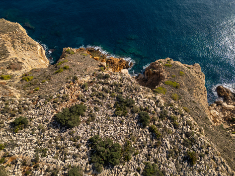 Aerial view of Cala Llebeig with rugged rocky cliffs Mediterranean sea and sparse vegetation in El Poble Nou de Benitatxell Valencian Community Spain.