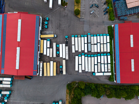 Aerial view of the Neuenstein Techno Zone logistics facility with rows of parked semi trailers industrial buildings with red roofs and solar panels in Neuenstein Baden Wurttemberg Germany. Aerial view of the Neuenstein Techno Zone logistics facility with rows of parked semi trailers industrial buildings with red roofs and solar panels in Neuenstein Baden Wurttemberg Germany.