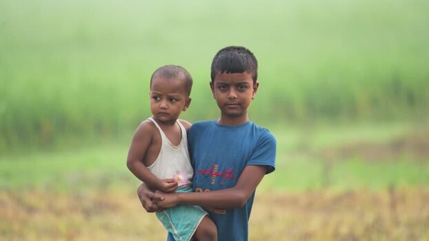 View of two children standing in a green field in Bogura Bangladesh.