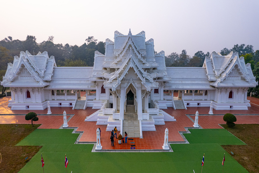 Aerial view of the Royal Thai Monastery with white ornate architecture tiled courtyard and visitors in Lumbini Nepal.