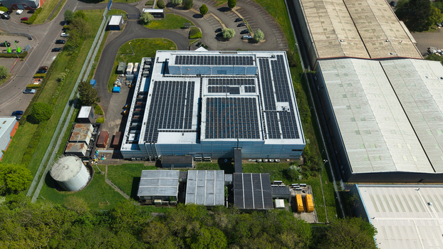 Aerial view of a modern data centre featuring extensive solar panels on its roof surrounded by industrial infrastructure and lush green trees in Wellingborough England United Kingdom. Aerial view of a modern data centre featuring extensive solar panels on its roof surrounded by industrial infrastructure and lush green trees in Wellingborough England United Kingdom.