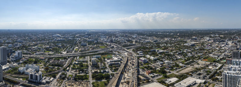 Aerial view of the cityscape meeting the horizon highways interweaving through a dense urban sprawl under a vast sky Miami Florida USA. Aerial view of the cityscape meeting the horizon highways interweaving through a dense urban sprawl under a vast sky Miami Florida USA.