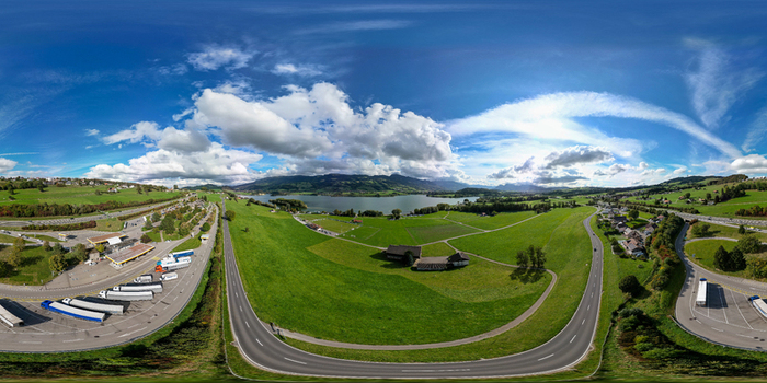 Aerial view of Station Restoroute Motel De La Gruyere overlooking Lake Gruyere with green fields and mountains under a cloudy sky in Pont en Ogoz Fribourg Switzerland. Aerial view of Station Restoroute Motel De La Gruyere overlooking Lake Gruyere with green fields and mountains under a cloudy sky in Pont en Ogoz Fribourg Switzerland.