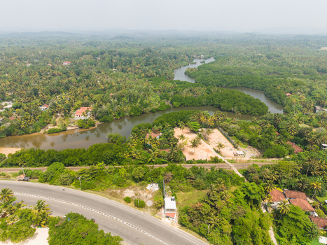 Aerial view of a winding river surrounded by lush tropical vegetation palm trees and scattered houses Ahangama Southern Province Sri Lanka. Aerial view of a winding river surrounded by lush tropical vegetation palm trees and scattered houses Ahangama Southern Province Sri Lanka.
