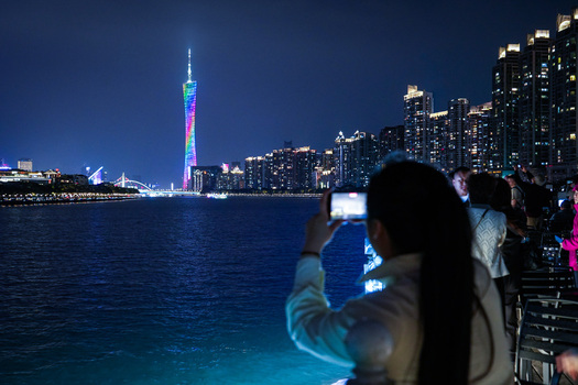 Guangzhou China 22 February 2024 View of the illuminated Canton Tower at night with people taking photos from the waterfront in Guangzhou Guangdong Province China. Guangzhou China 22 February 2024 View of the illuminated Canton Tower at night with people taking photos from the waterfront in Guangzhou Guangdong Province China.