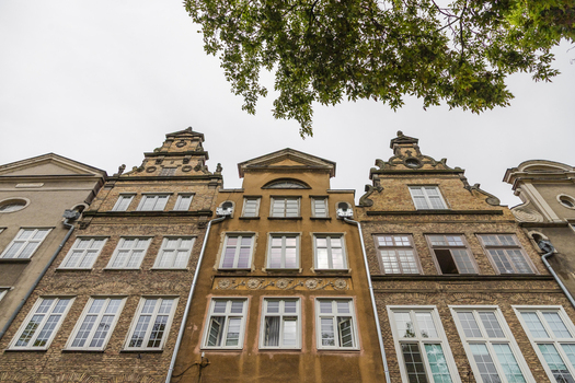 View of historic narrow townhouses with ornate gables and brick facades in the old town of Gdansk Pomeranian Voivodeship Poland. View of historic narrow townhouses with ornate gables and brick facades in the old town of Gdansk Pomeranian Voivodeship Poland.