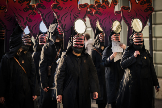 Basel Switzerland 10 March 2025 View of hooded figures with masks and mirrors marching in the Fasnacht parade a sea of black against the muted city backdrop. Basel Switzerland 10 March 2025 View of hooded figures with masks and mirrors marching in the Fasnacht parade a sea of black against the muted city backdrop.