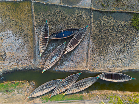 Aerial view of traditional wooden boats resting on dry cracked mud flats and a narrow water channel Moheskhali Upazila Chittagong Division Bangladesh. Aerial view of traditional wooden boats resting on dry cracked mud flats and a narrow water channel Moheskhali Upazila Chittagong Division Bangladesh.