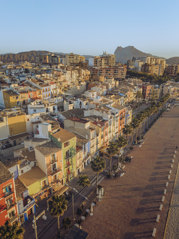 Aerial view of colorful houses along the waterfront promenade with palm trees and mountains in the background La Vila Joiosa Valencian Community Spain. Aerial view of colorful houses along the waterfront promenade with palm trees and mountains in the background La Vila Joiosa Valencian Community Spain.