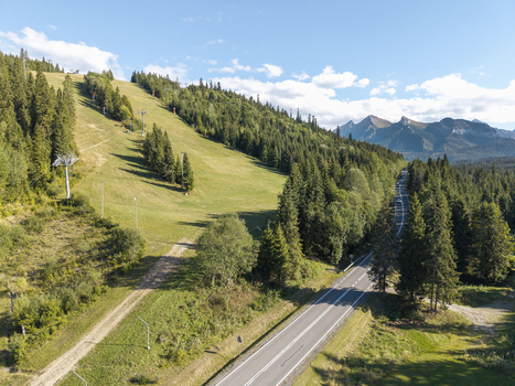 Aerial view of the Tatra Mountains ski slope surrounded by lush pine forests and a winding road in Poland. Aerial view of the Tatra Mountains ski slope surrounded by lush pine forests and a winding road in Poland.