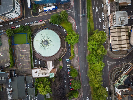 Aerial view of St Catherine of Siena Catholic Church green dome and an adjacent sports court surrounded by urban roads and trees in Birmingham England United Kingdom.