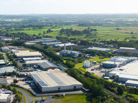 Aerial view of an industrial park with large warehouses solar panels and a manufacturing facility surrounded by green fields and trees in Lisburn Northern Ireland United Kingdom. Aerial view of an industrial park with large warehouses solar panels and a manufacturing facility surrounded by green fields and trees in Lisburn Northern Ireland United Kingdom.