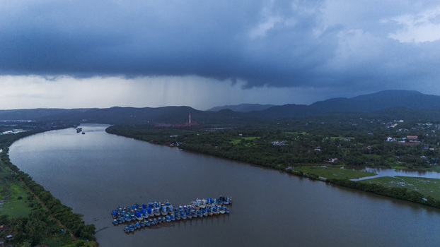 Aerial view of Sal River with fishing boats moored together under a dramatic stormy sky and dark clouds in South Goa Goa India.