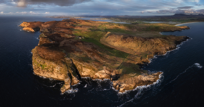 Aerial view of Horn Head peninsula featuring dramatic sea cliffs and green pastures overlooking the Atlantic Ocean in County Donegal Ireland.