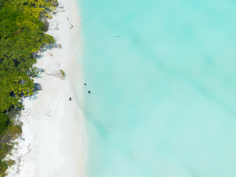 Aerial view of turquoise waters meet the pristine white sands of the beach contrasting with the lush green vegetation Thuraakunu Thiladhunmathee Uthuruburi Maldives. Aerial view of turquoise waters meet the pristine white sands of the beach contrasting with the lush green vegetation Thuraakunu Thiladhunmathee Uthuruburi Maldives.