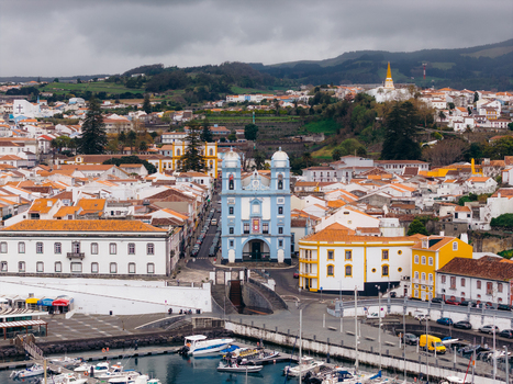 Aerial view of the blue Church of Misericordia and historic white buildings with terracotta roofs near the harbor Angra do Heroismo Azores Portugal.