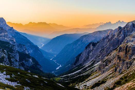View of the Auronzo valley in the Dolomites at sunset with dramatic rocky peaks pine forests and a winding river below in Auronzo Veneto Italy.