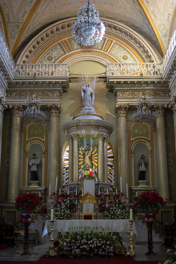 View of the ornate altar inside a historic church featuring a central religious statue golden columns crystal chandeliers and festive floral arrangements. Guanajuato Guanajuato Mexico. View of the ornate altar inside a historic church featuring a central religious statue golden columns crystal chandeliers and festive floral arrangements. Guanajuato Guanajuato Mexico.