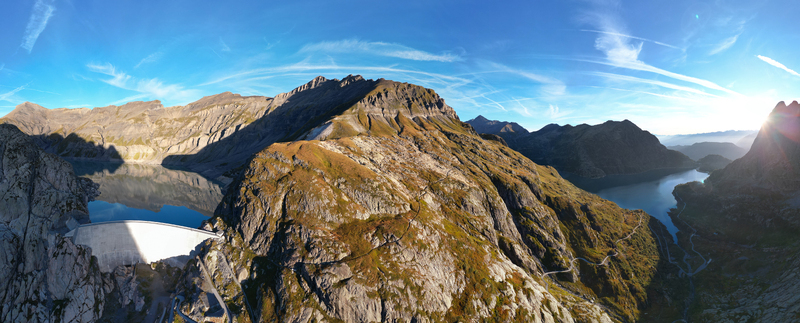 Aerial view of Barrage d Emosson dam and reservoir surrounded by rugged alpine mountains under a clear blue sky in Finhaut Valais Switzerland.